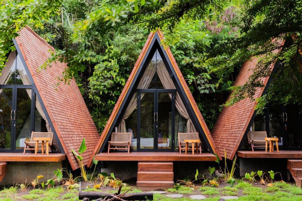 Multiple A-frame cabins surrounded by forest